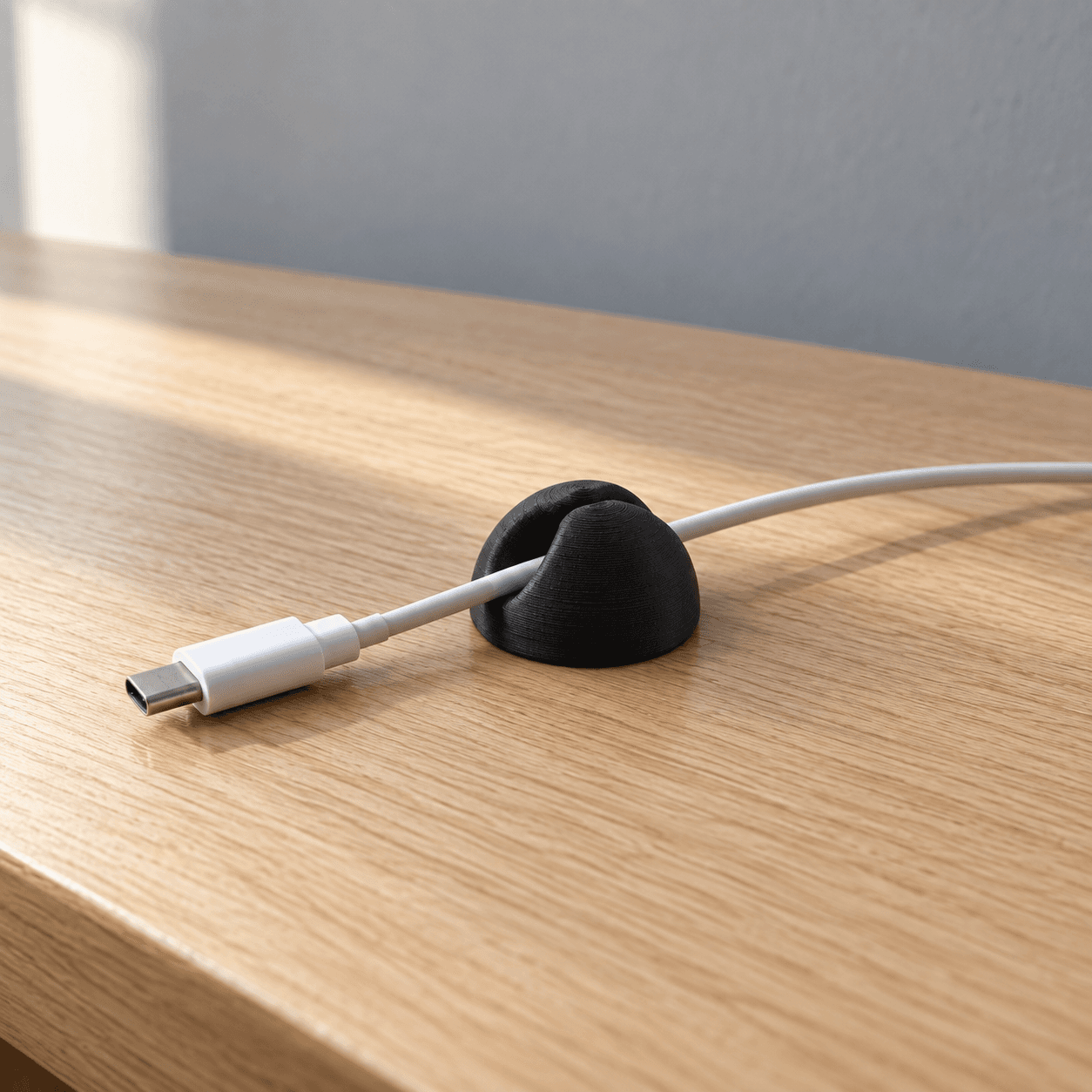 Black cable holder on a desk keeping a charging cable within reach